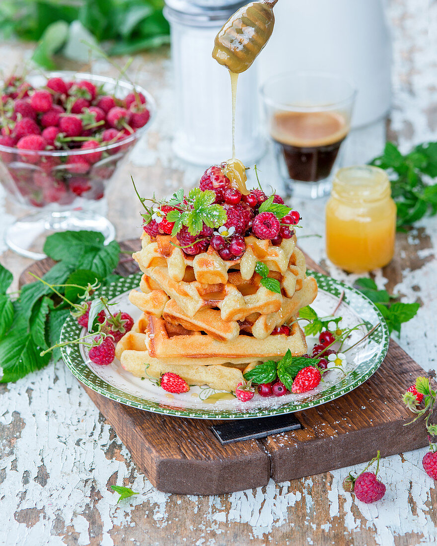 Honig auf Waffeln mit Beeren träufeln