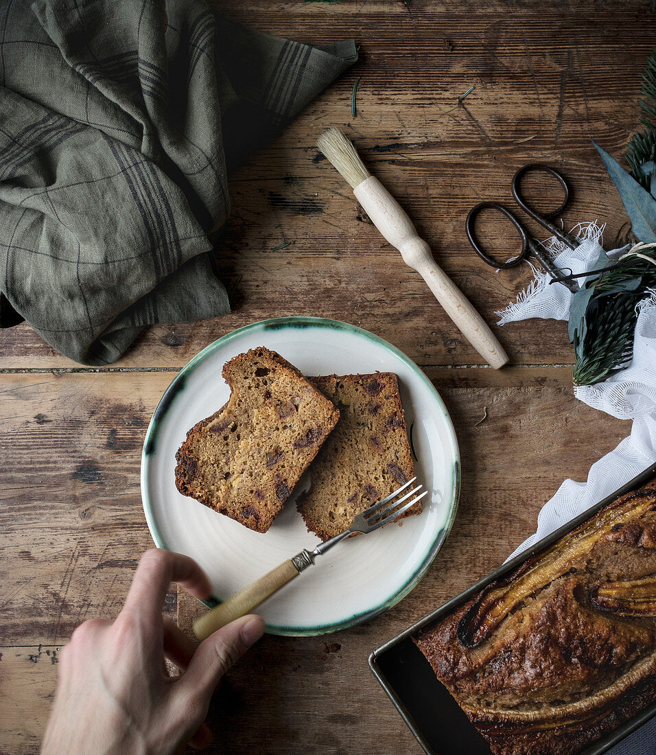 Healthy banana bread in container and slices in a plate on wooden background