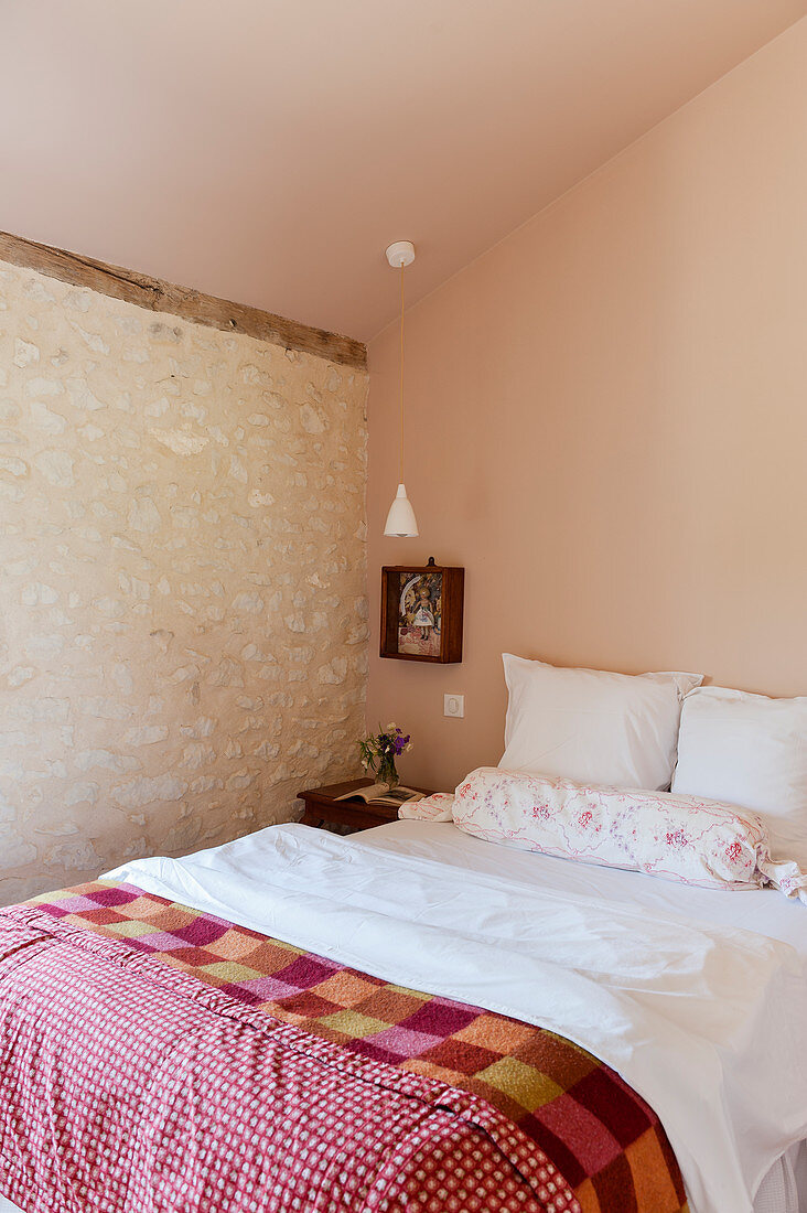 Rustic bedroom with stone wall and vintage-style quilt on bed