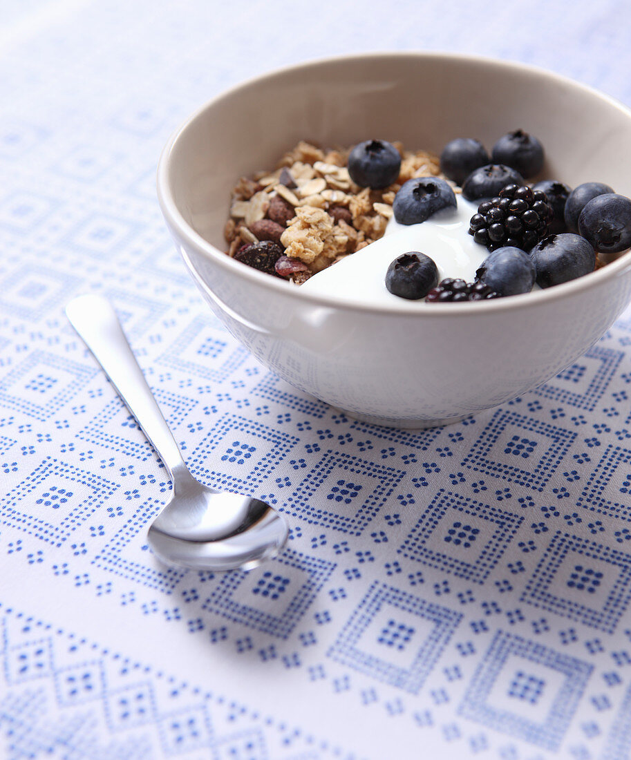 Muesli with yoghurt, blueberries and blackberries in a small bowl