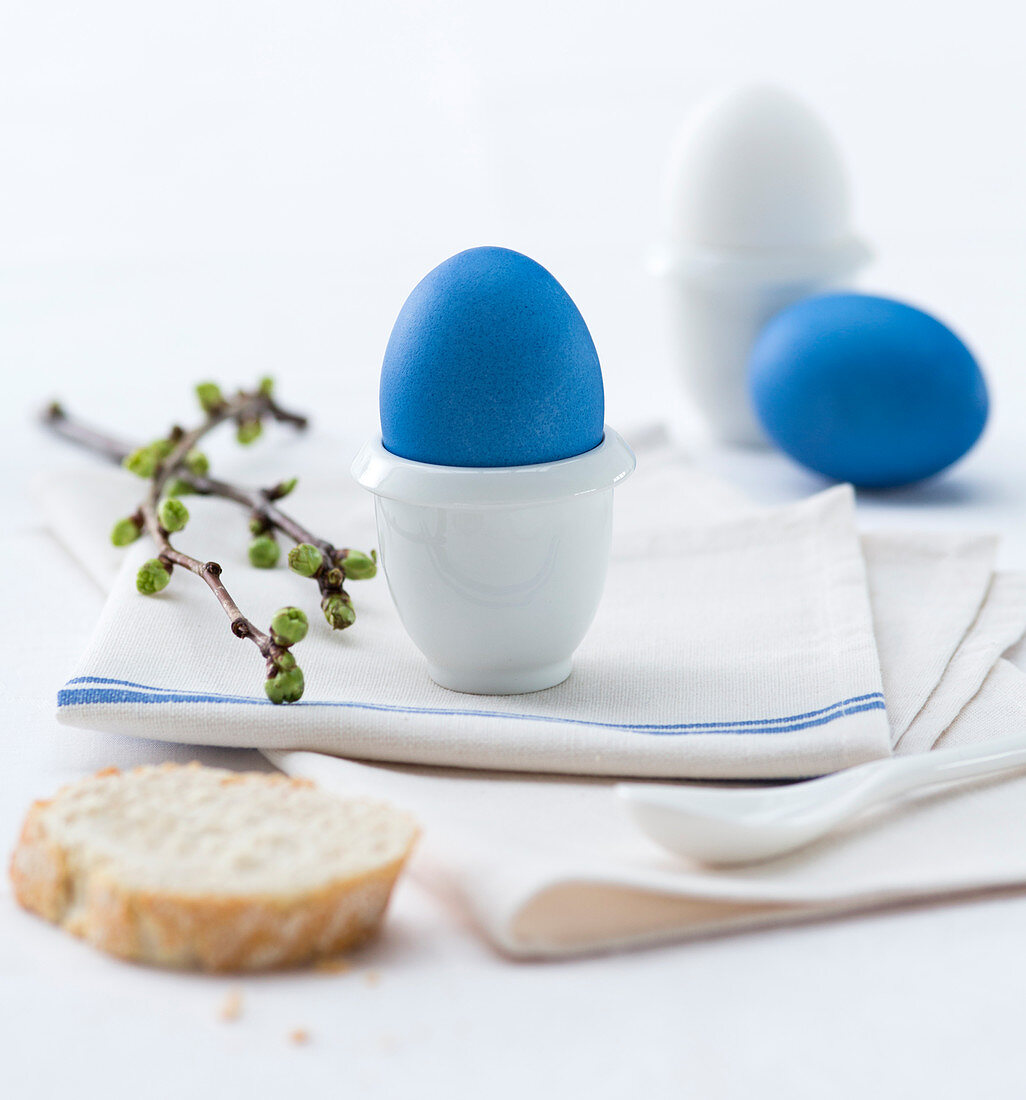 Blue dyed easter eggs in egg cups on a cloth napkin