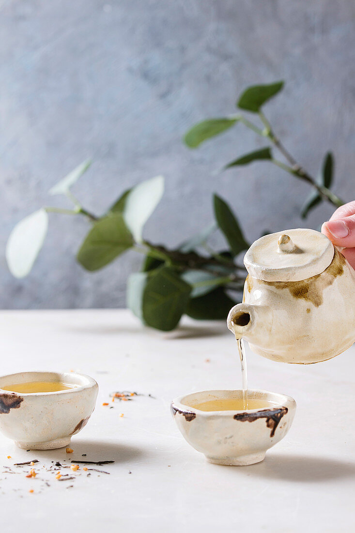 Traditionelles, chinesisches Teegeschirr aus Lehm, grüner Tee wird eingeschenkt
