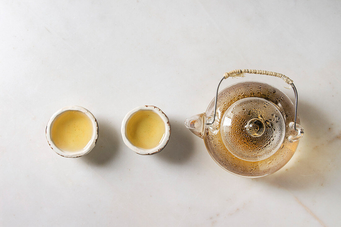Grüner Tee in Teekanne und in traditionellen, chinesischen Teeschalen aus Lehm
