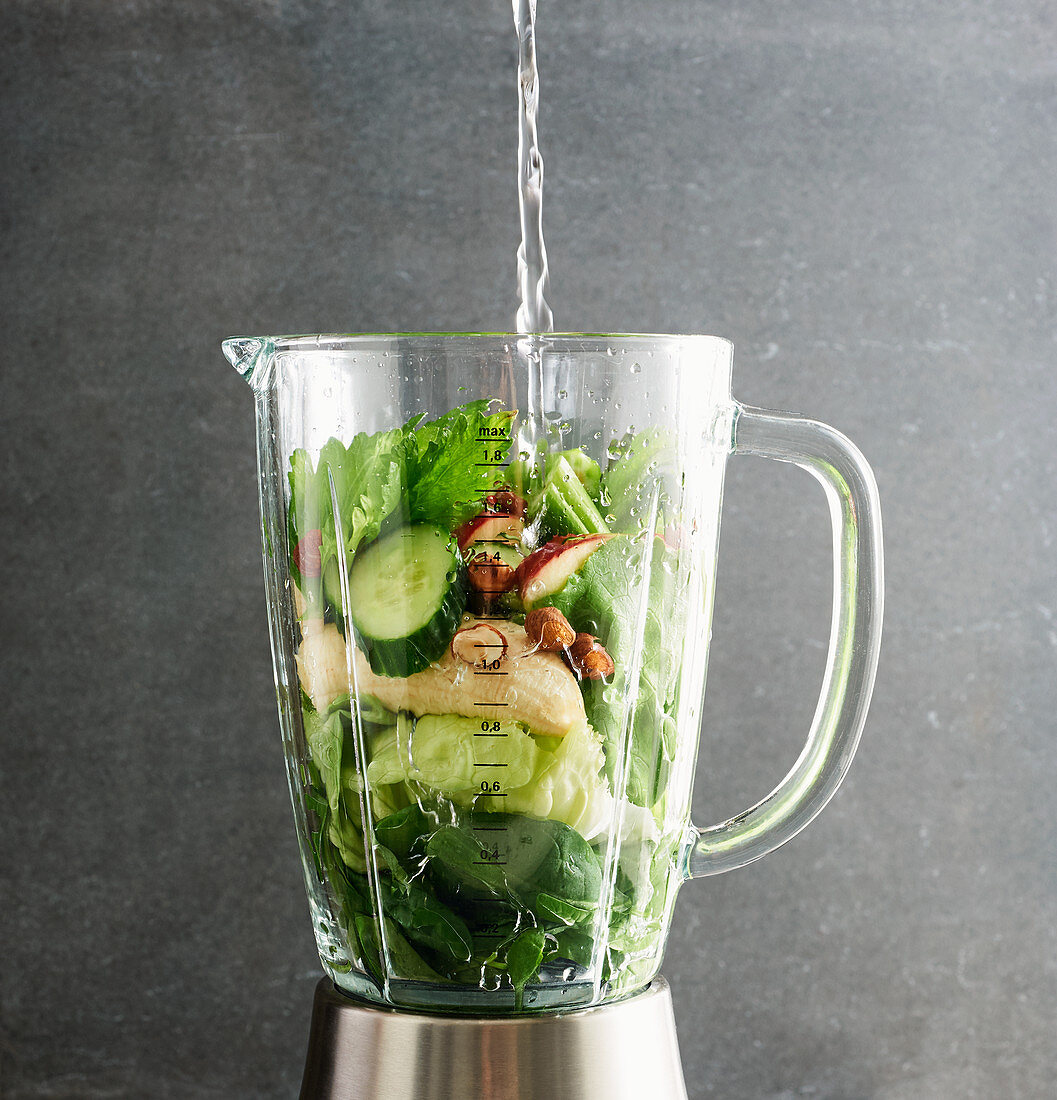 Mineral water being added to ingredients in a blender