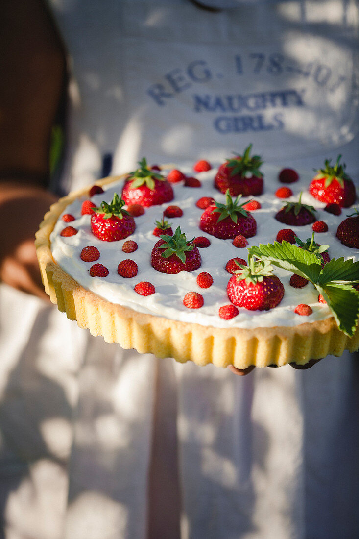 Mascarpone tart garnished with garden and wild strawberries