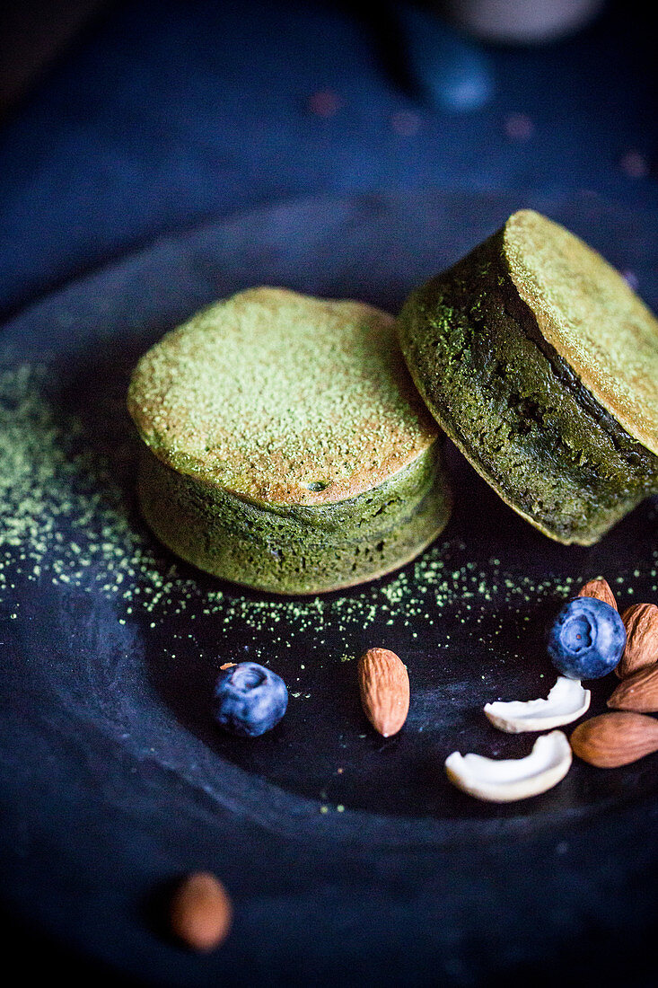 Matcha-Pancakes mit Nüssen, Mandeln und Blaubeeren auf Teller