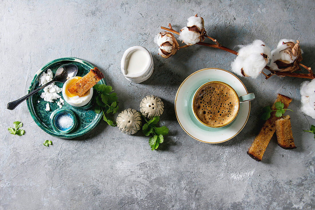 Frühstück mit weichgekochtem Ei, Brotsticks und Tasse Kaffee auf Tisch