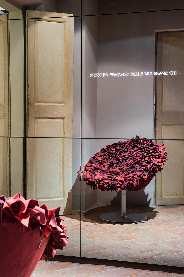 Roter Designersessel im Spiegelschrank mit Leuchtschrift