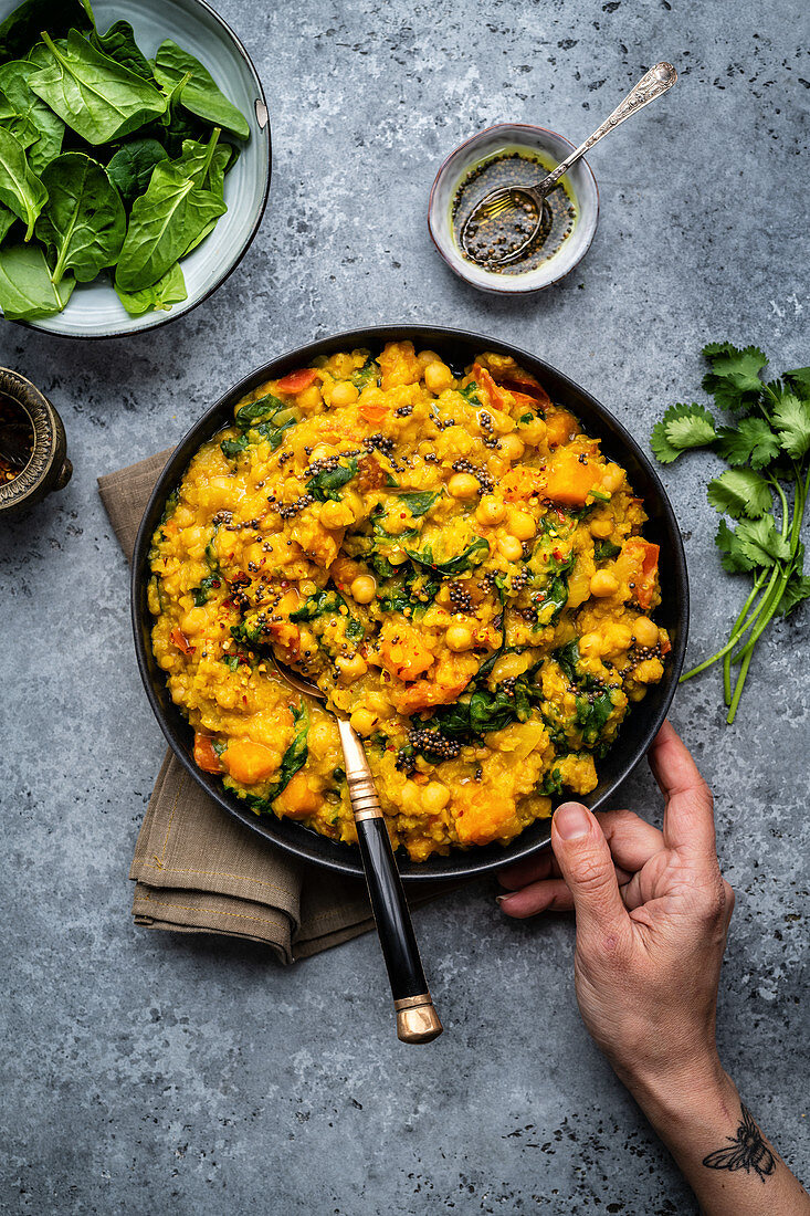 Vegan red lentil, chickpea and squash dahl with spinach in a bowl (India)