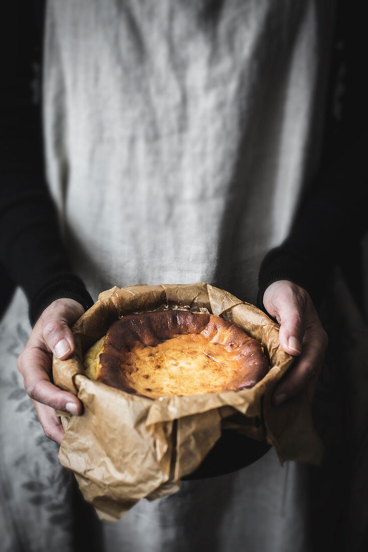 Hands holding cooking pot with cheese cake