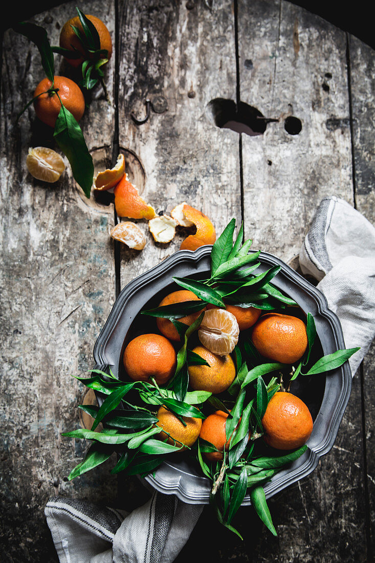 Mandarinen mit Blättern auf rustikalem Holztisch