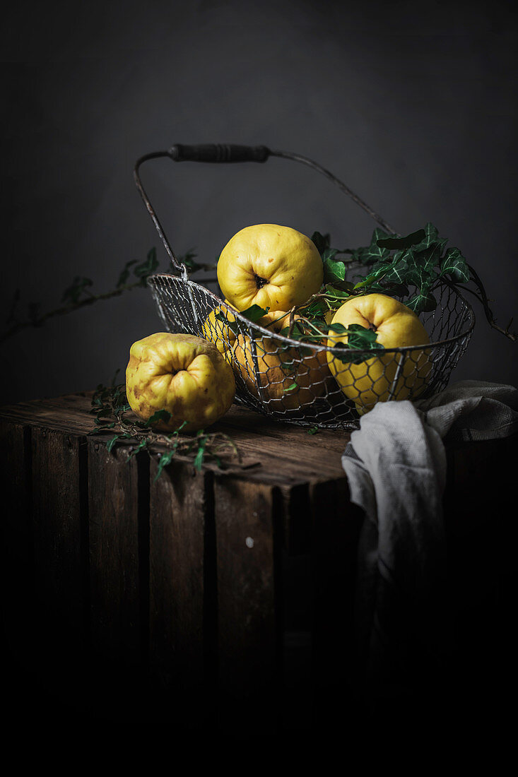 Ripe yellow apple-quinces placed in basket on dark wooden background