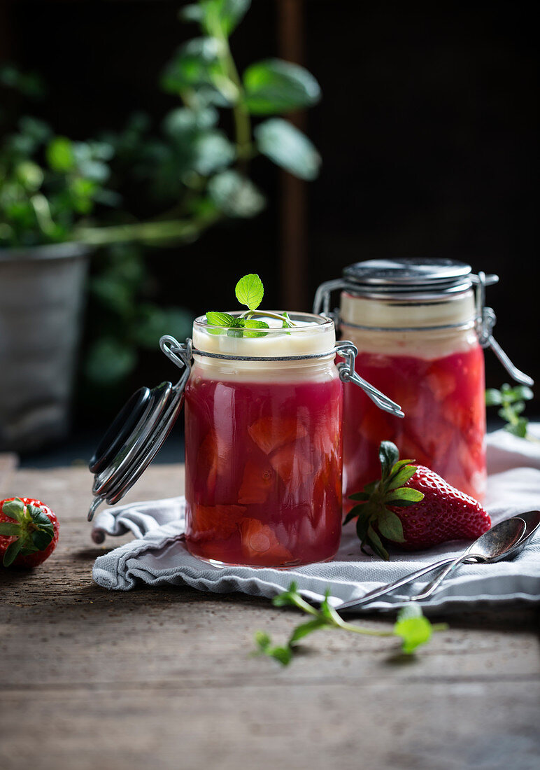 Zwei Gläser vegane Erdbeergrütze mit frischen Früchten und Vanillesauce