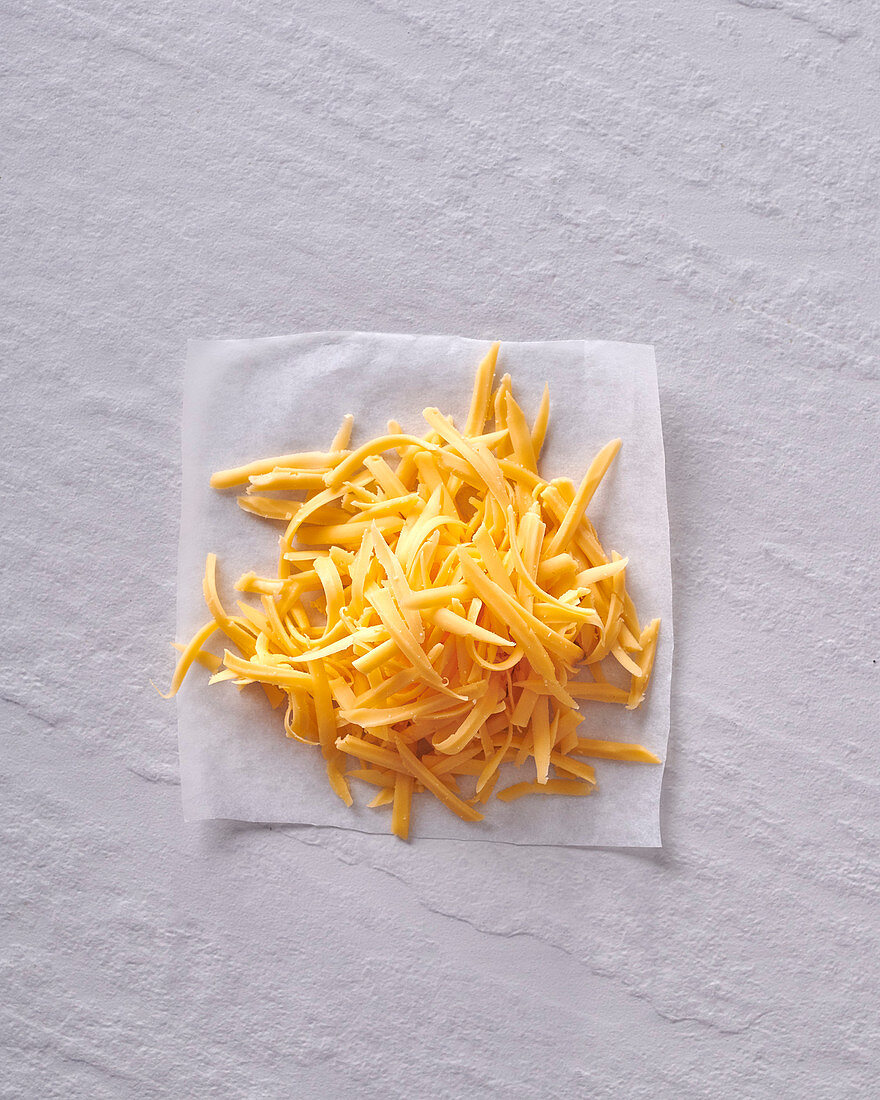 A heap of grated cheddar on paper