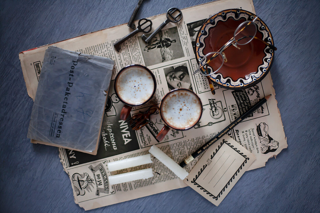 Old newspaper, address book, coffee cups, candles and key