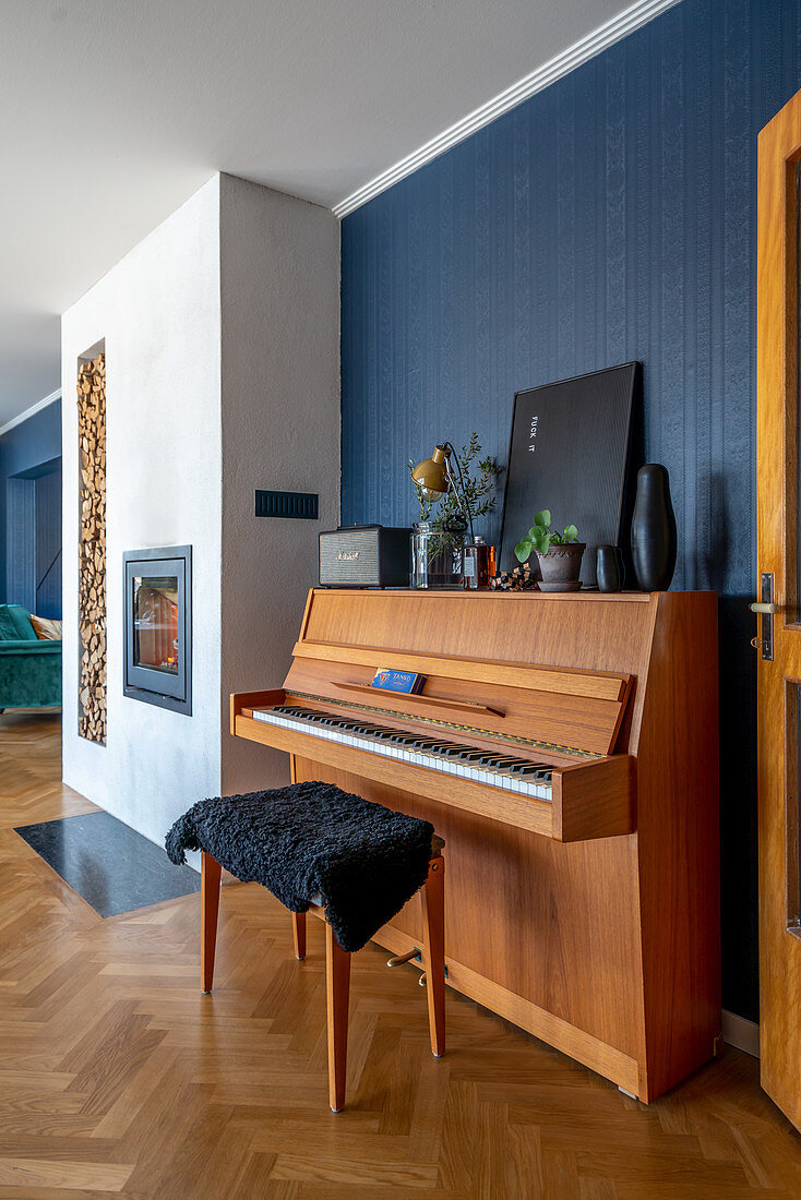Piano and piano stool in open-plan interior with blue wall