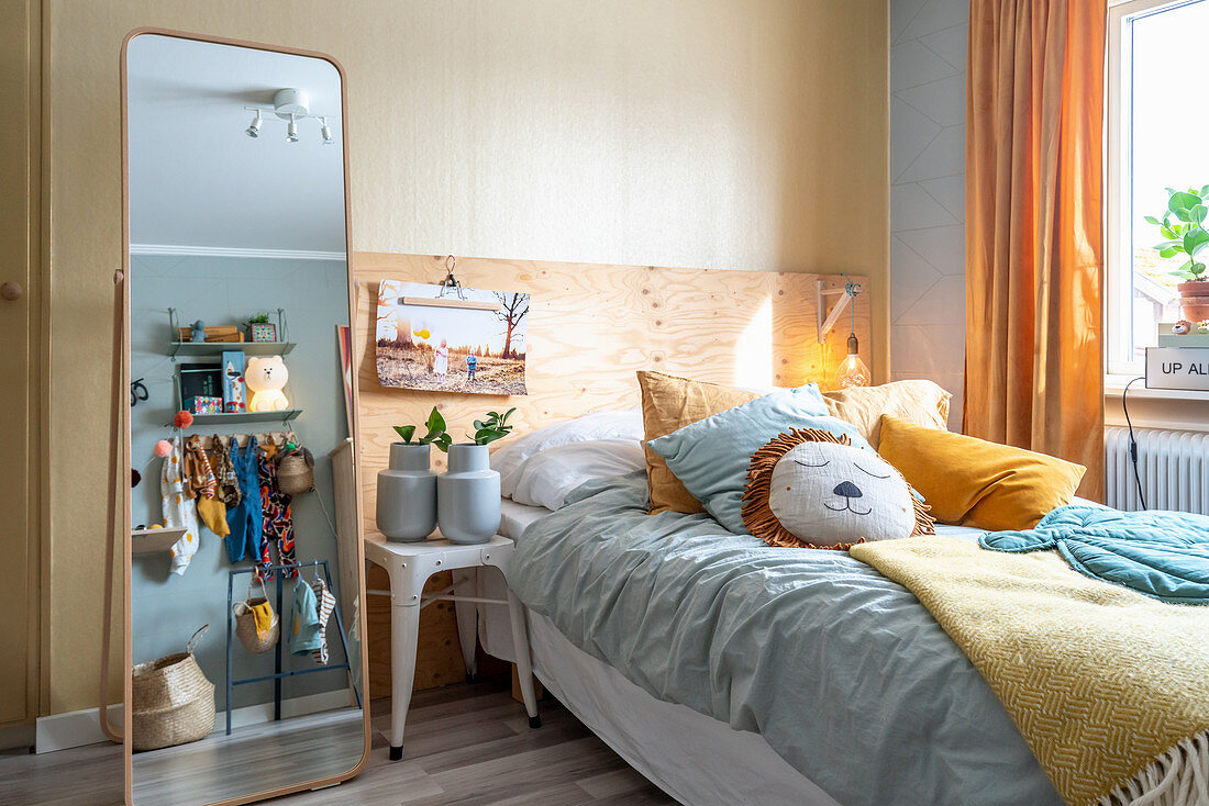 Free-standing mirror next to stool used as bedside table and bed in child's bedroom