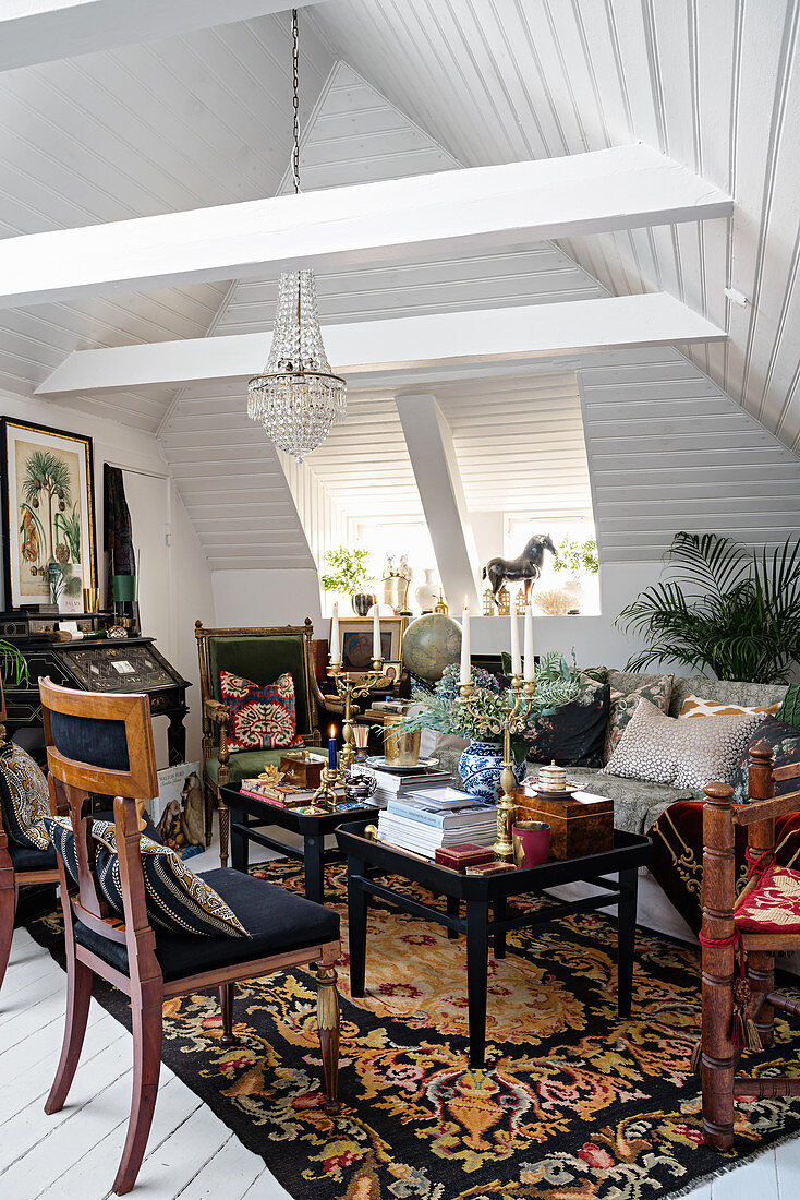 Antique chairs, sofa and side tables in lavishly decorated attic interior