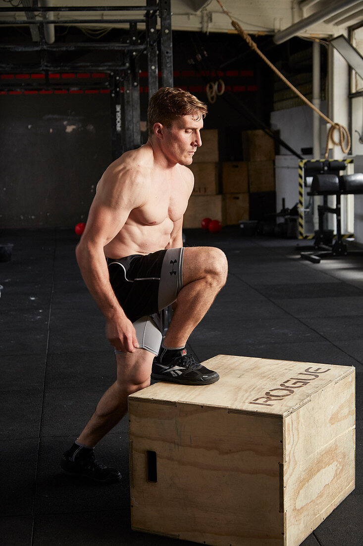 A young man performing explosive step-ups on a vaulting box