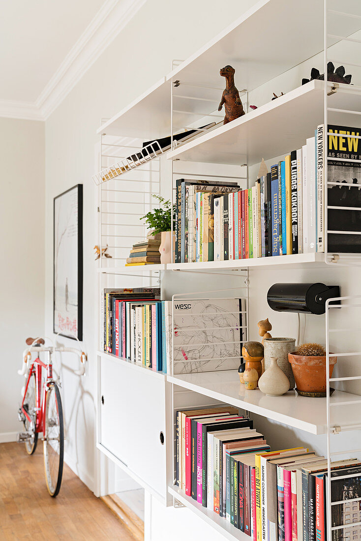 Books and ornaments on white shelves and bicycles in living room