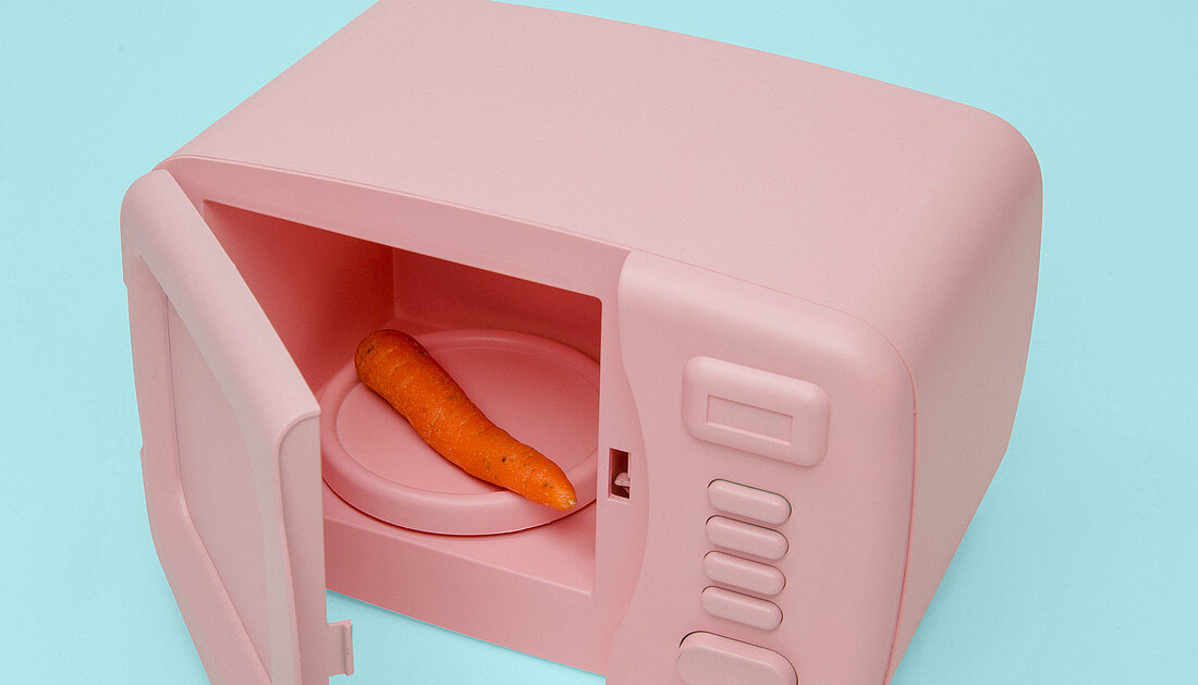 A carrot inside a small pink microwave