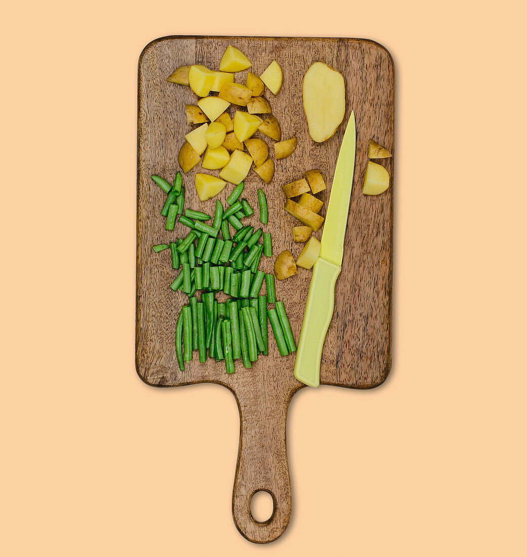 Chopped green beans and potatoes on a wooden board