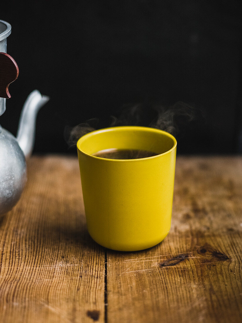 Heisser Kaffee im Becher auf Holzfläche