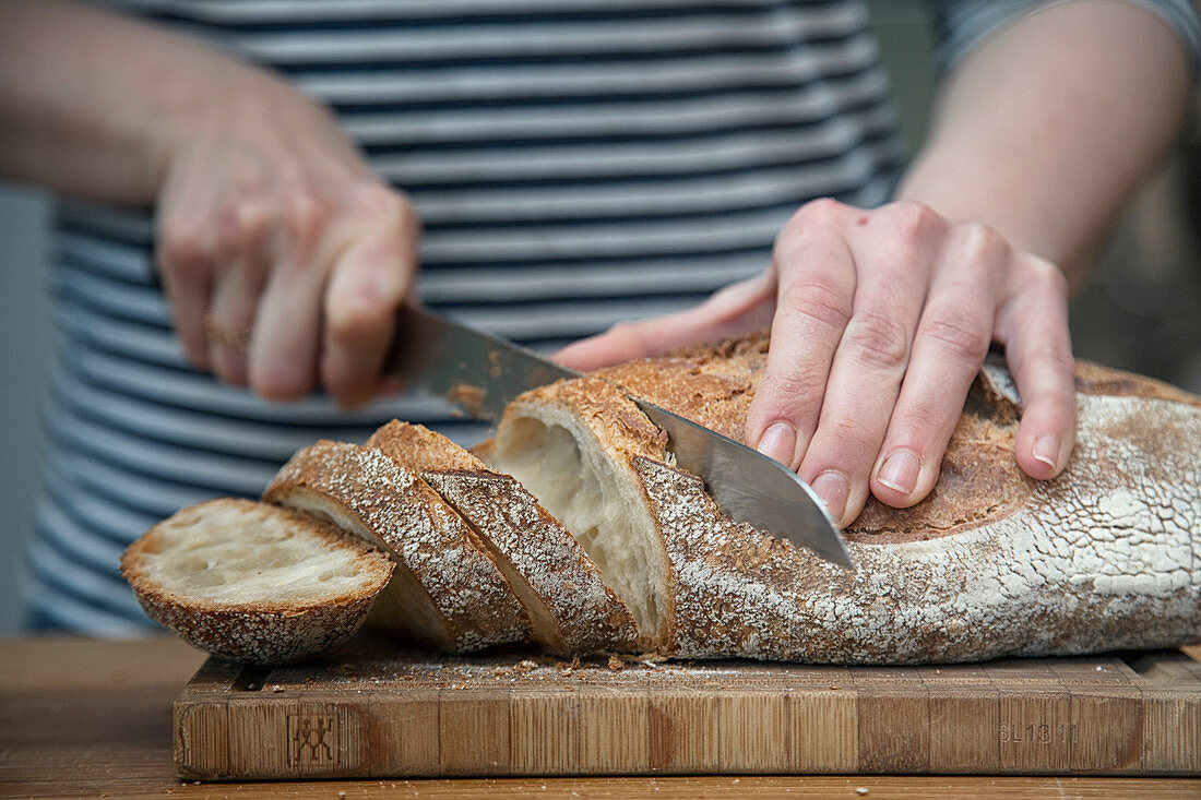 Frau schneidet frisch gebackenes Brot