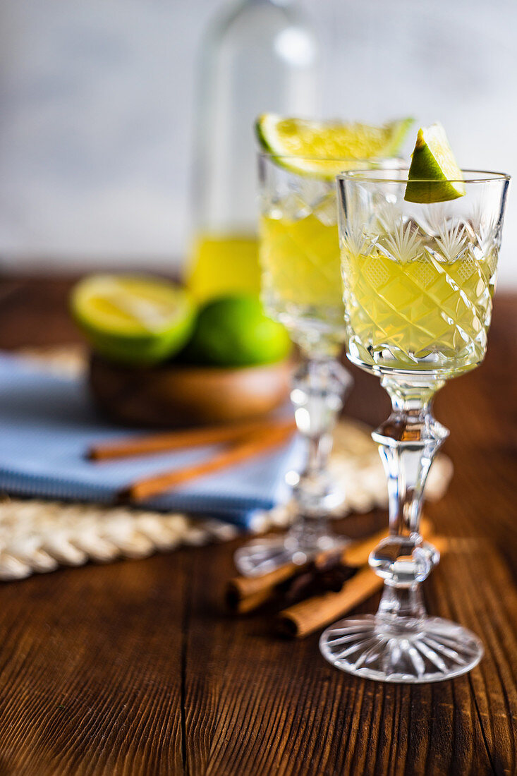 Traditional italian lemon alcohol drink limoncello with pieces of lemon and rosemary herb