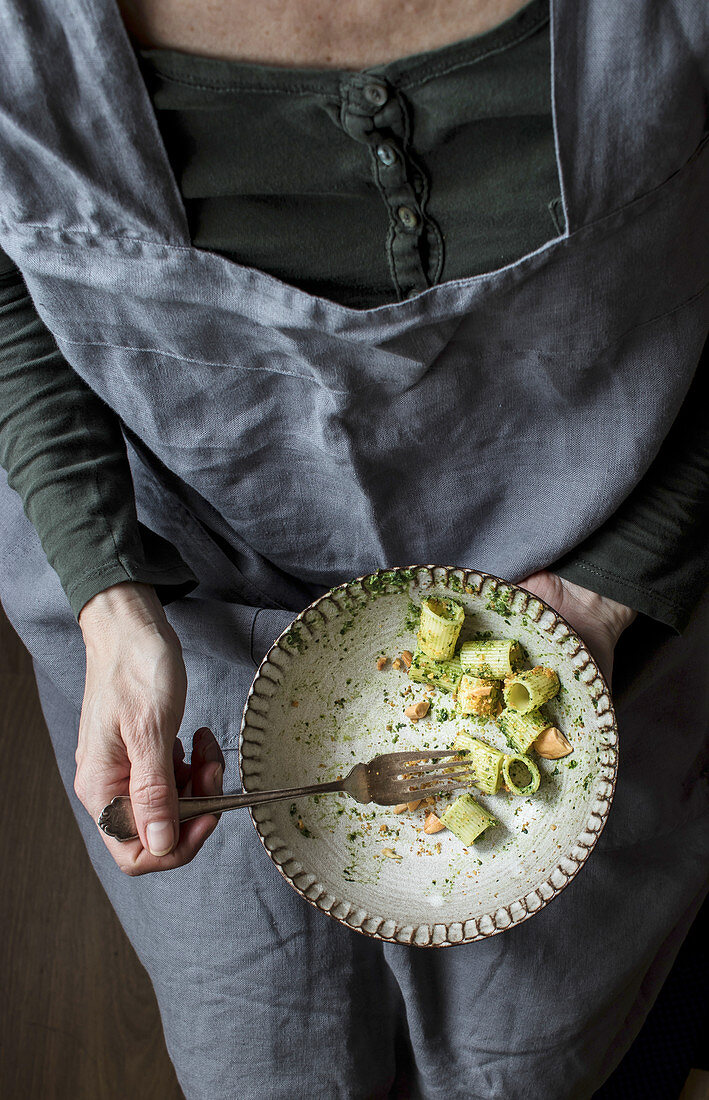 Frau mit fast leergegessenem Pastateller