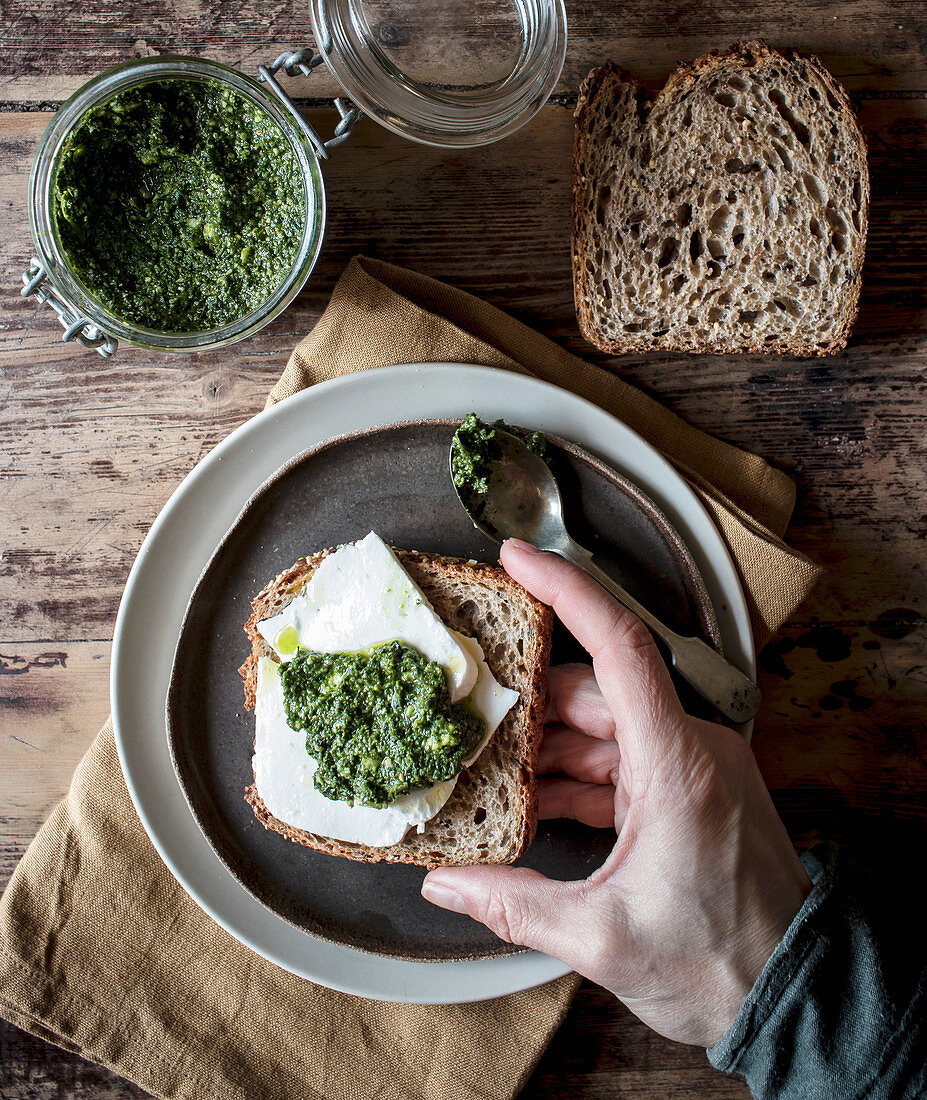 From above plate with tasty rye toast with cheese and fresh pesto placed