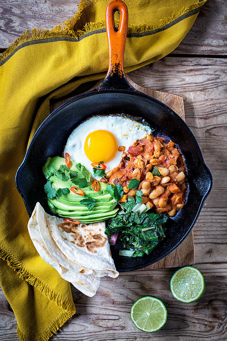 Frying pan with Beans, Avocado, Tomatoes, Eggs and Bread