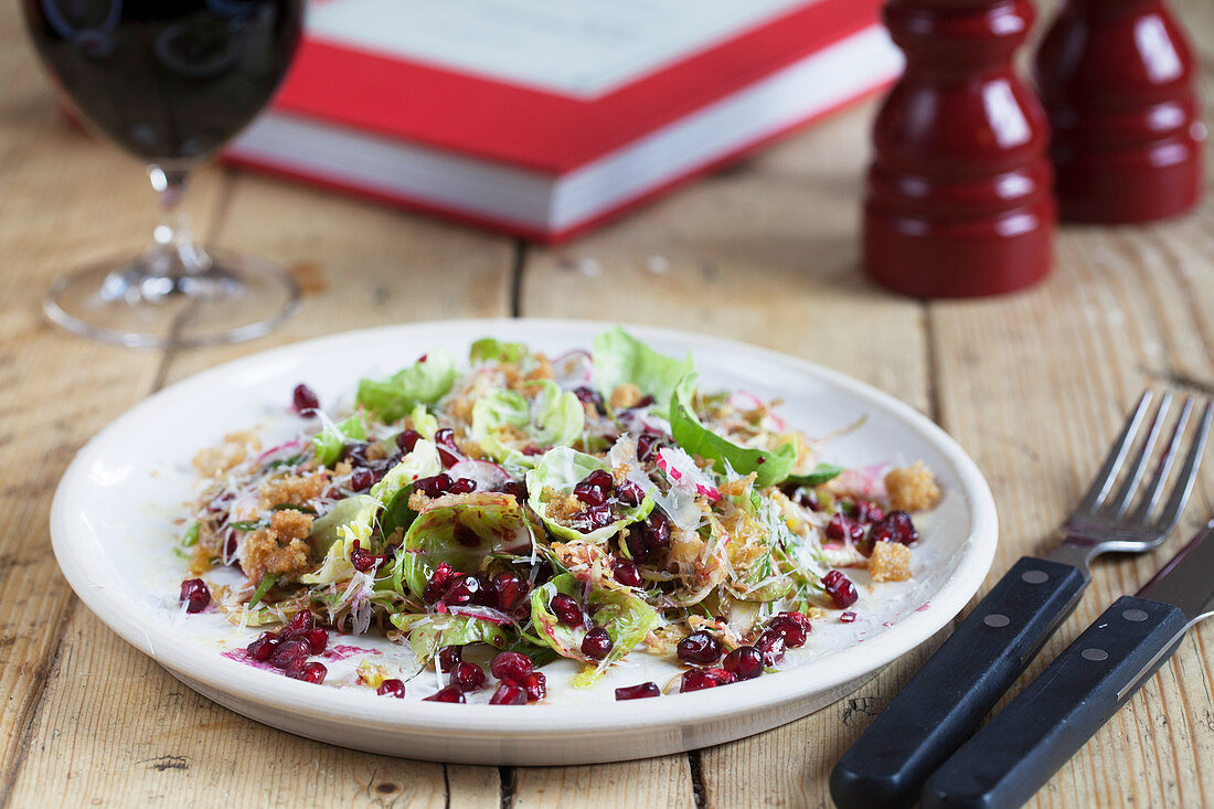 Beetroot, Sprout and Pomegranite Salad on a wooden table with glass of Red Wine
