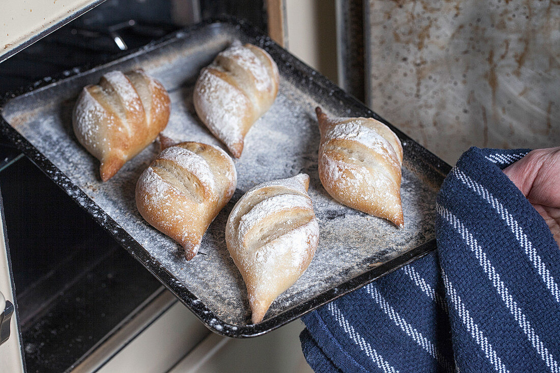 Lifestyle shot of Fresh bread rolls being taken out of an oven