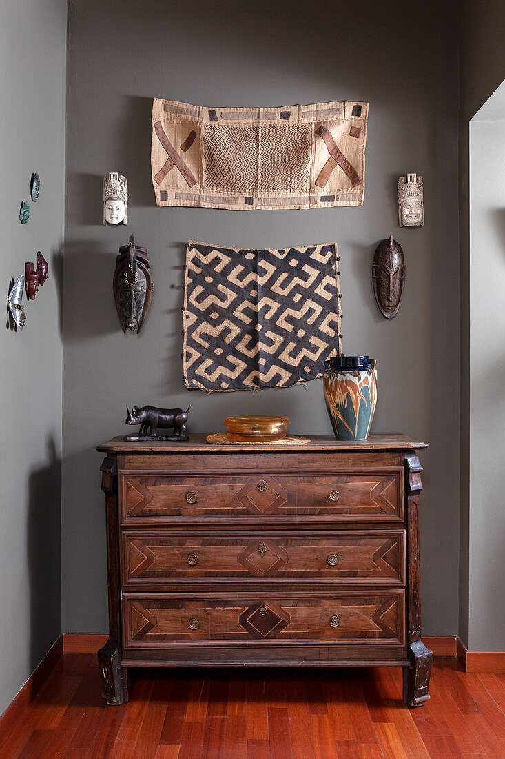 Carved walnut chest of drawers in hallway with grey walls