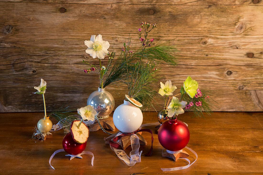 Christmas-tree baubles used as vases for hellebores and white pine branches