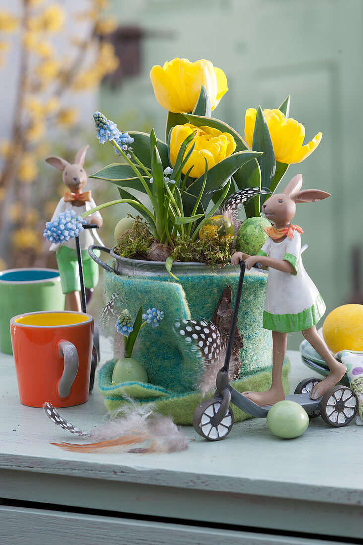 Lustige Osterdekoration mit Tulpen und Traubenhyazinthen im Filzmantel, Ostereier, Osterhasen auf Roller