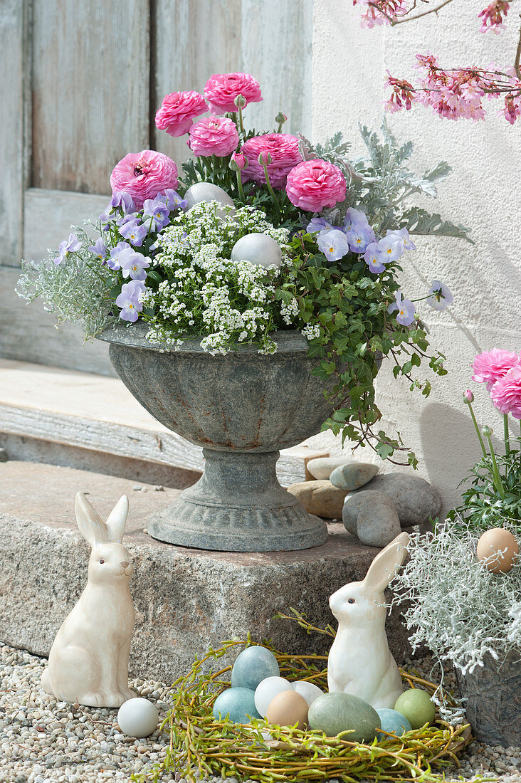 Blumenspindel mit Frühlingsblumen und Weidenkranz als Osternest mit Ostereiern und Osterhasen