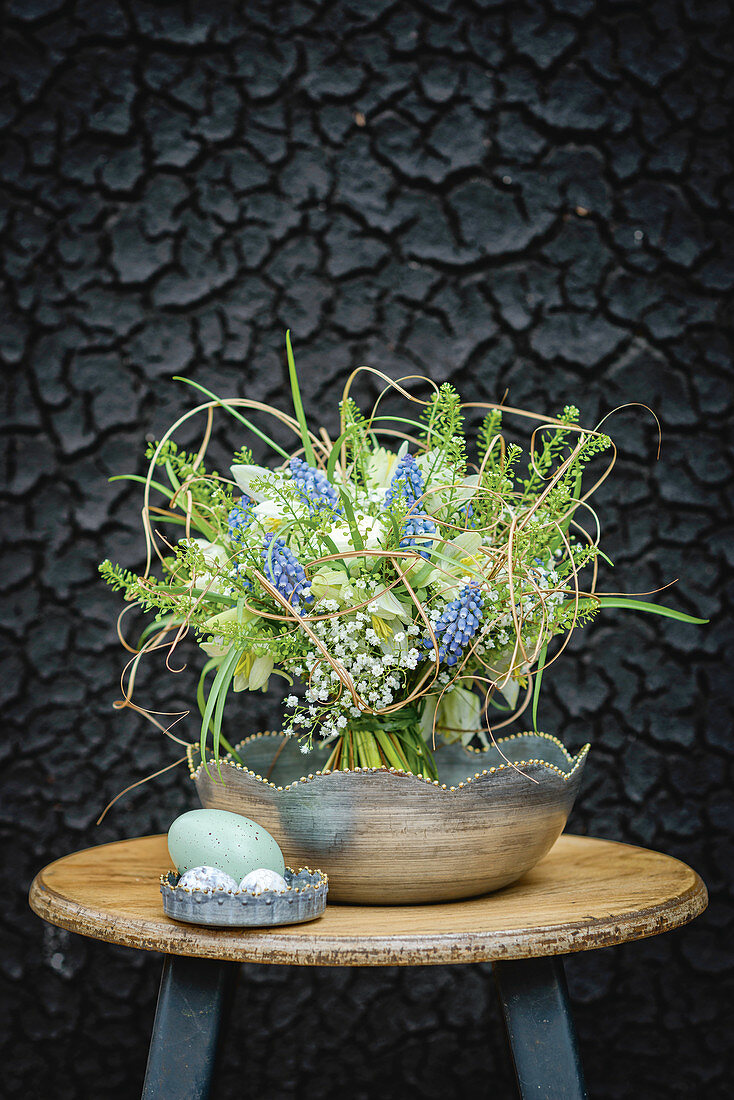 Bouquet of spring flowers on stool in front of sooty wall