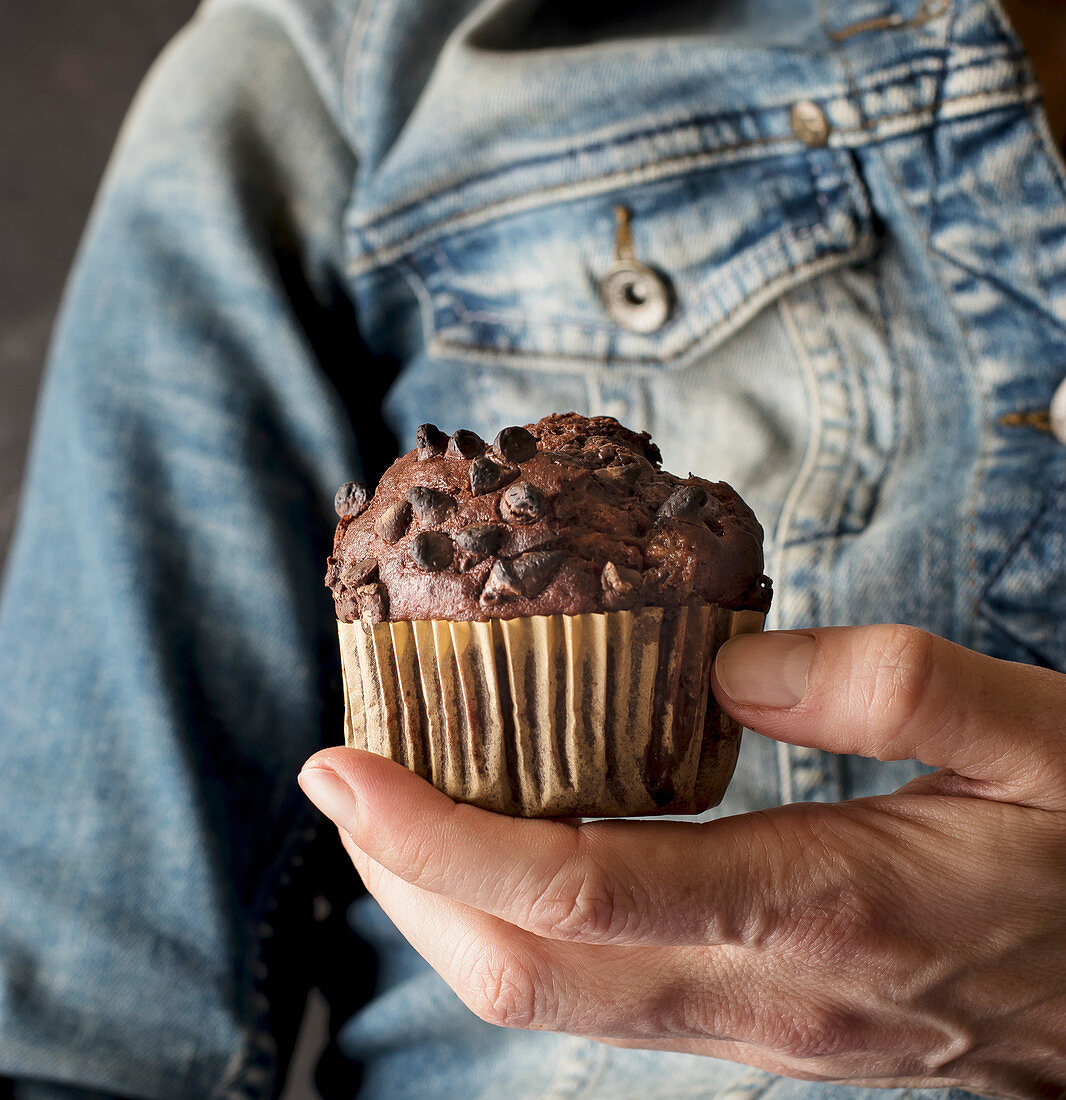 Unrecognizable female holding delicious chocolate banana muffin in hand