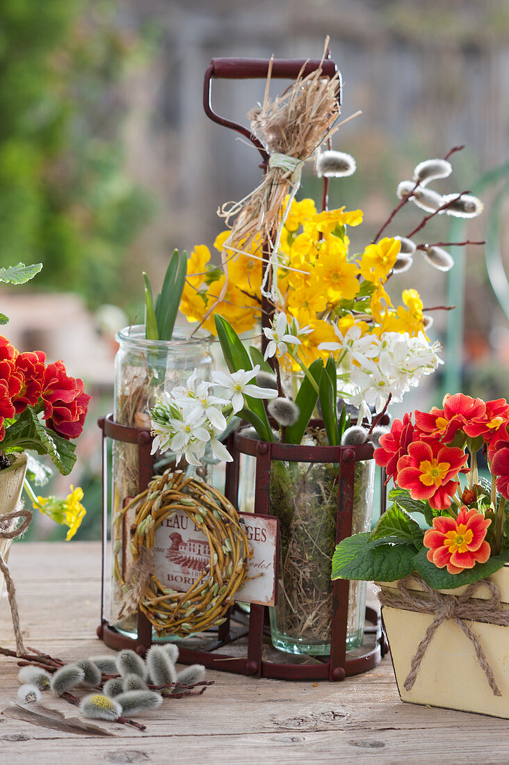 Small spring decorations with primroses, willow wreaths and pussy willow in a milk bottle carrier