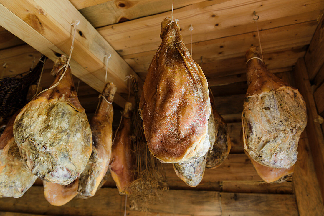 Kumpiak-Schinken aus Polen trocknen in einem Holzschrank aus Buchenholz