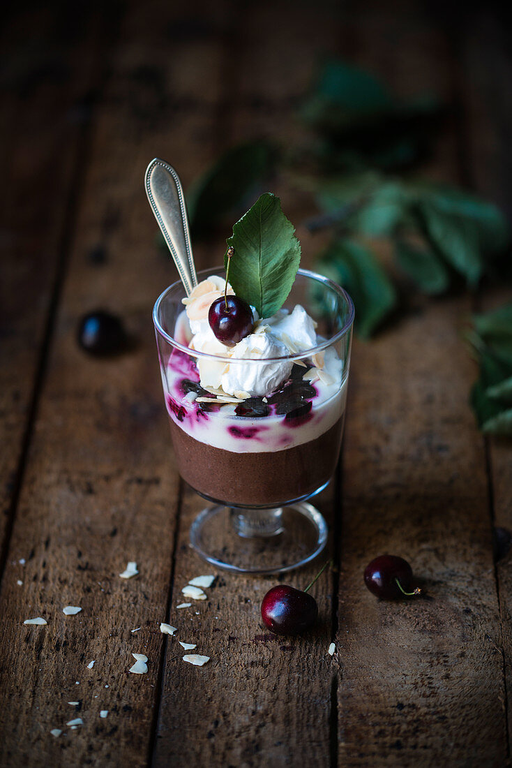 Vegan chocolate semolina pudding with soya yoghurt, cherries, whipped cream and flaked almonds