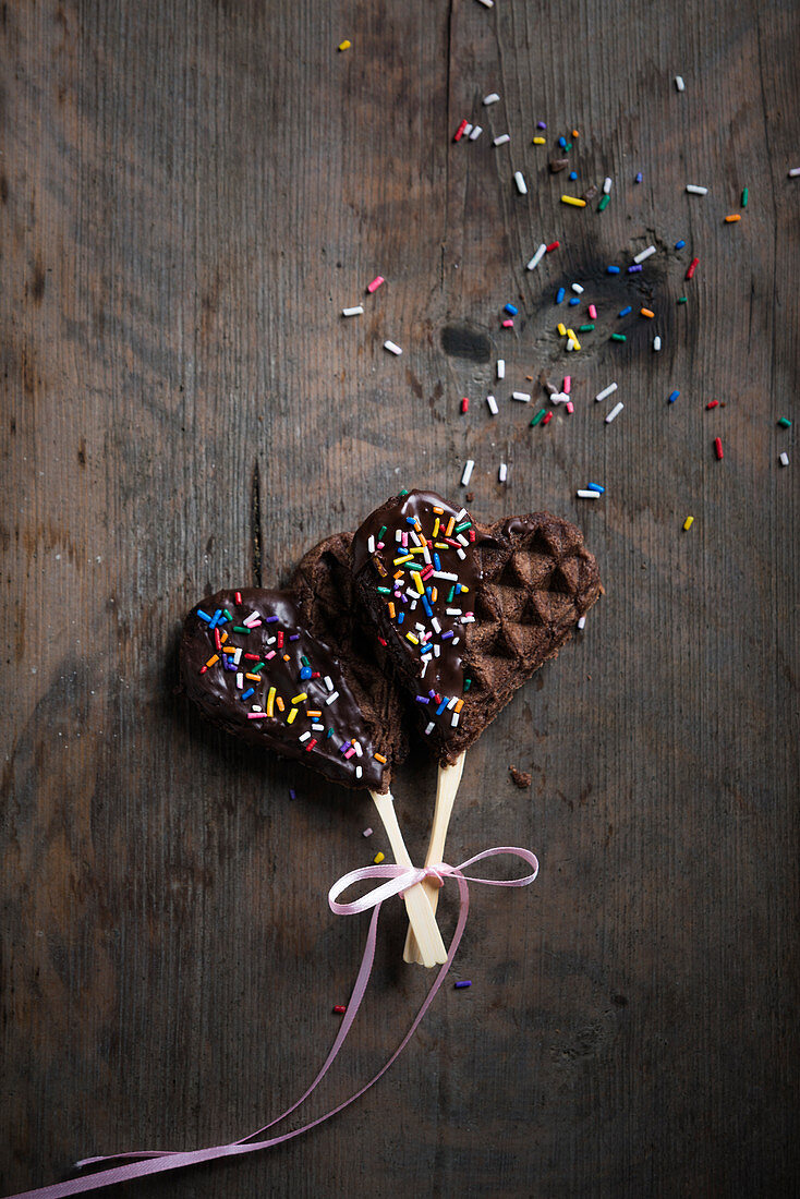 Vegan waffle hearts on sticks with chocolate glaze and colourful sugar sprinkles