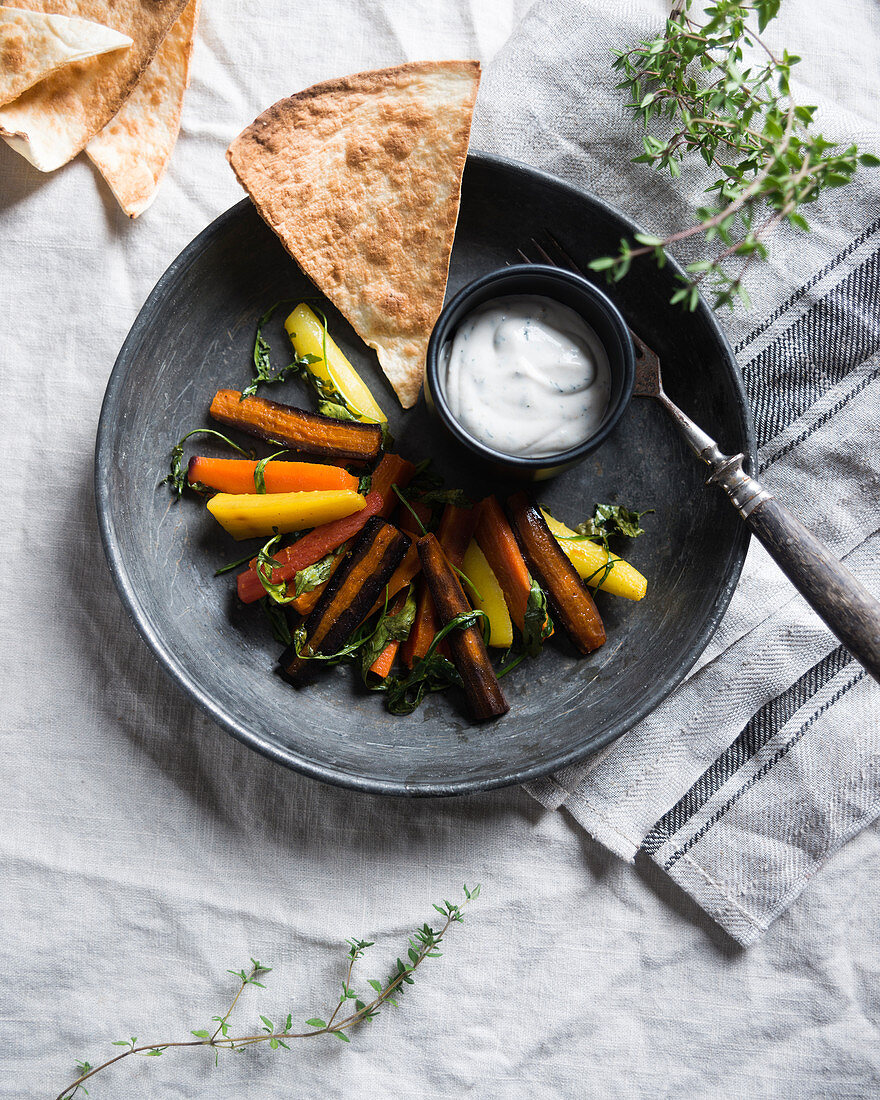Colourful oven-baked carrots with rocket and a vegan herb dip