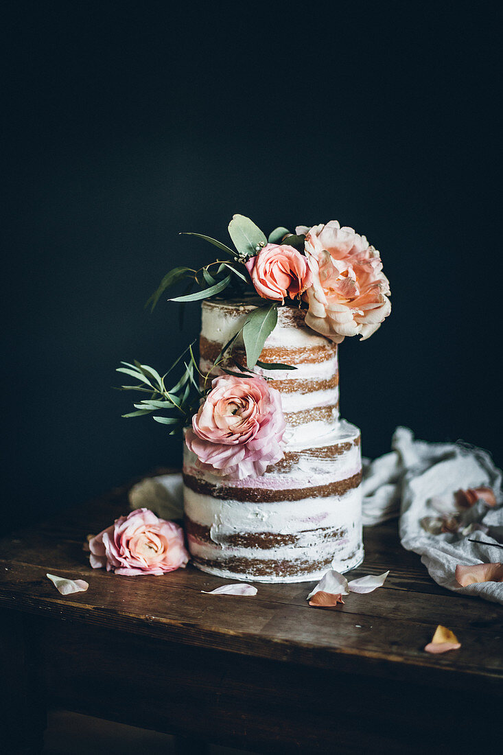 A wedding cake (naked cake) with pastel-coloured summer flowers