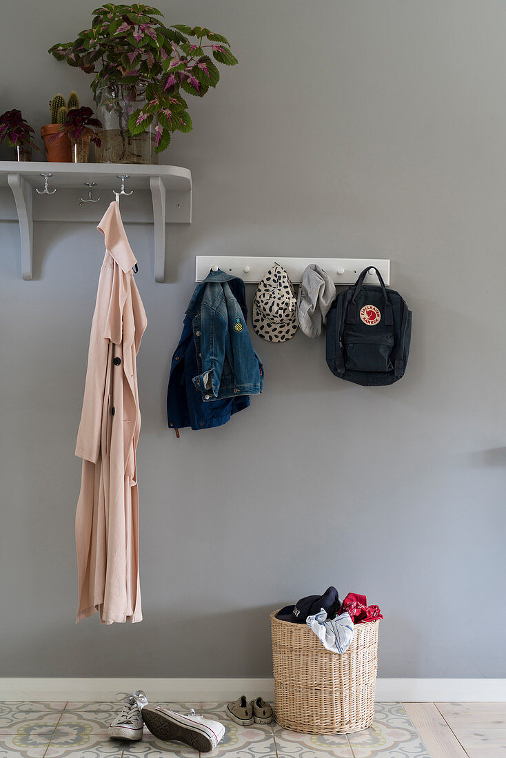 Coat rack and row of hooks on grey wall in foyer