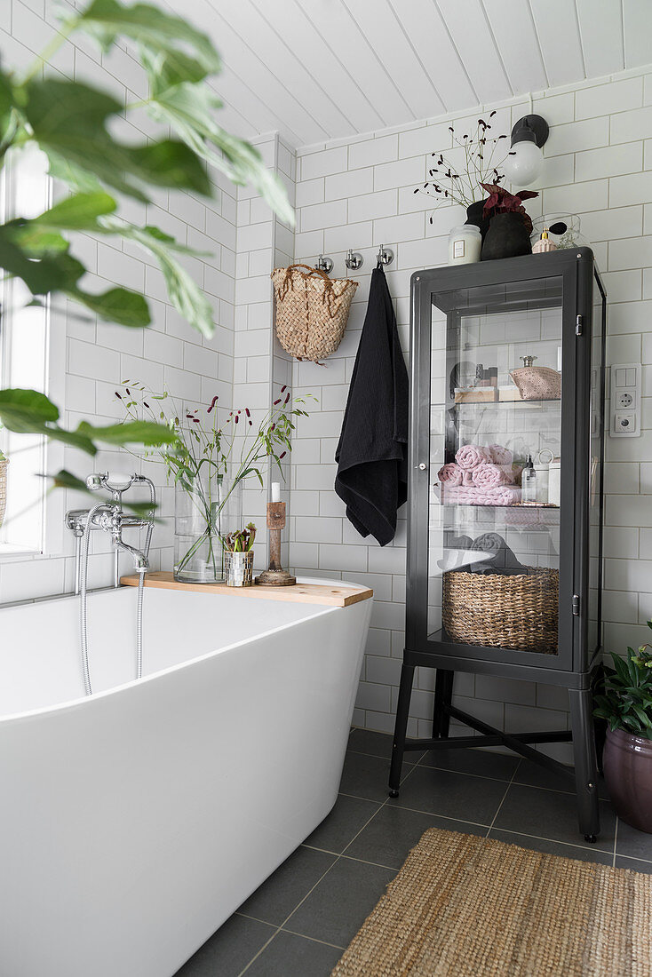 Black display case next to modern, free-standing bathtub