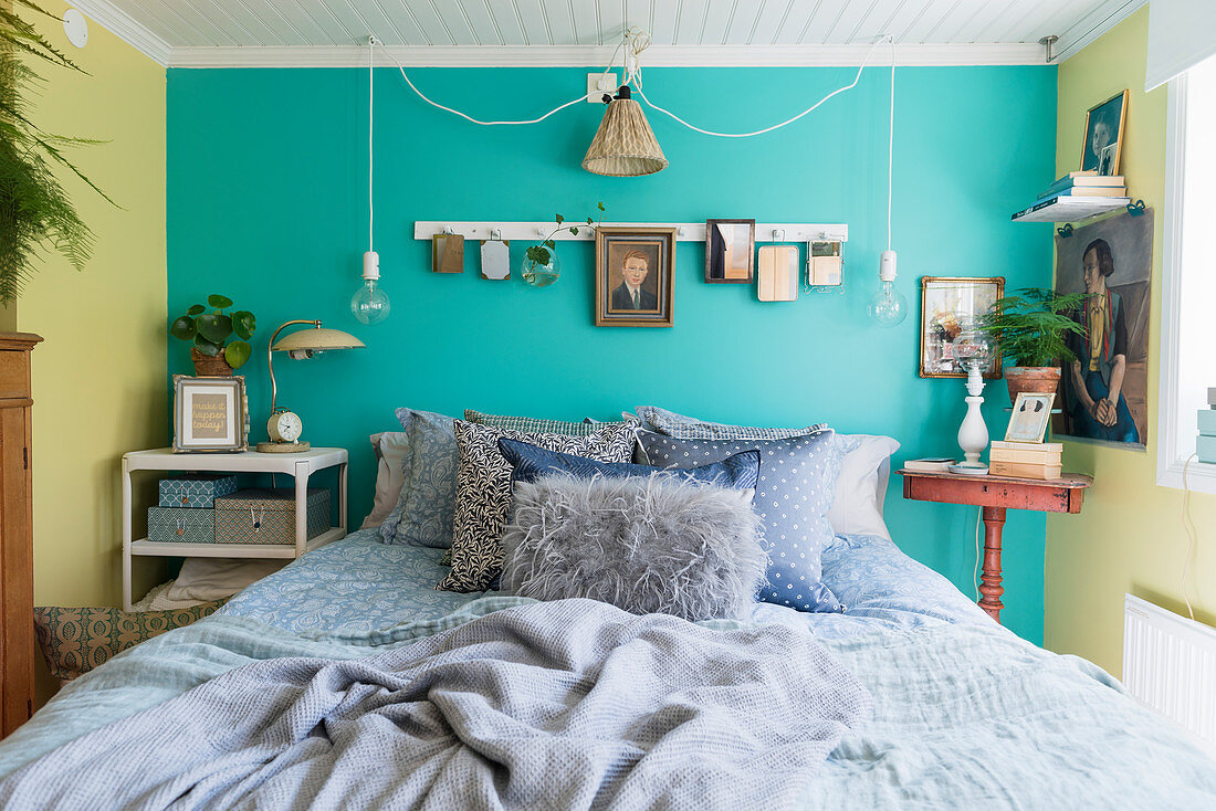 Bed against turquoise wall in bedroom with vintage-style ambience
