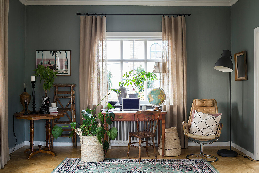 Antique table below lattice window in interior with grey walls